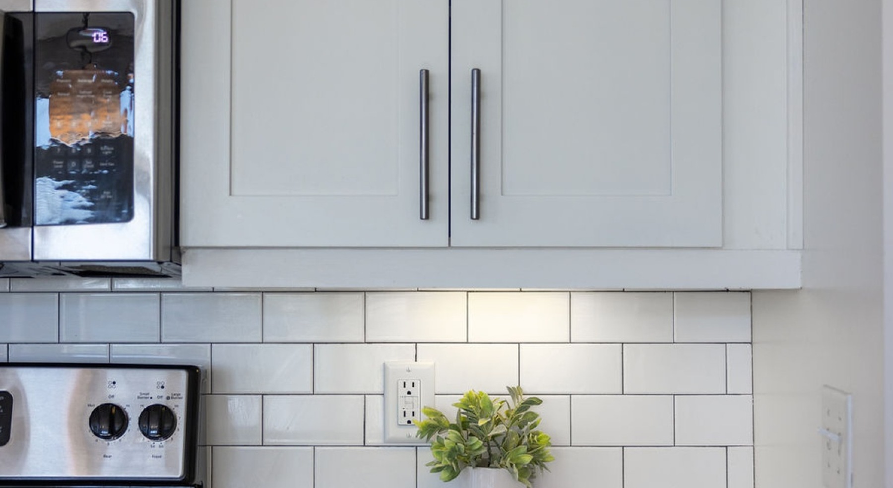 tiled white backsplash and stainless steel appliances